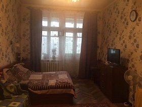 диван, большая кровать, ваза на столе, телевизор на комоде, ковер на полу комнаты со старым ремонтом квартиры СССР