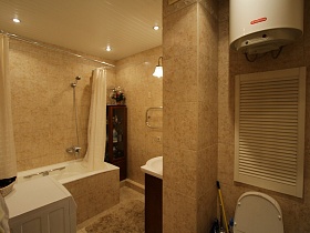 коричневый шкаф с туалетными принадлежностями у белой ванны со светлой шторой,обогревательный бак над санузлом в ванной комнате квартиры государственного служащего