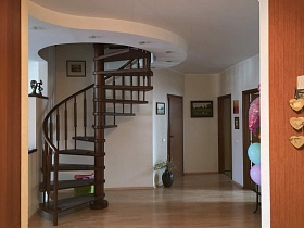 коричневая деревянная винтовая лестница в светлой студии современной квартиры на последнем этаже жилого дома