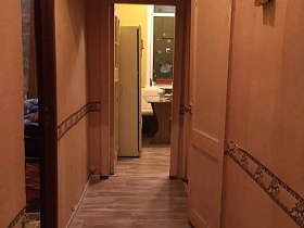 электросчетчик на бежевой стене прихожей с антресолью и открытыми дверьми в спальню и на кухню двухкомнатной квартиры СССР